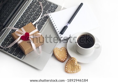 laptop, gift box tied with ribbon, red heart, cup of coffee, heart-shaped cookies, notebook and pen on a white background. gift for valentine's day.