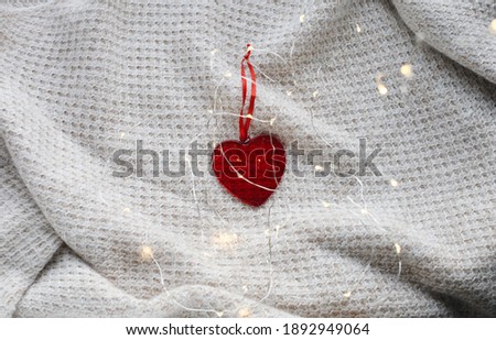 Beautiful Valentine's Day photo with glossy glass heart and warm plaid background. Flat lay photography