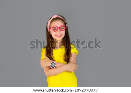 Cute girl and pink children's smart watch isolated on gray background. Trend color 2021. Protection and control.