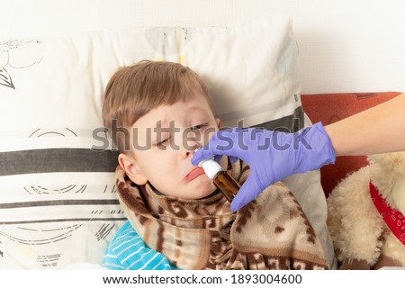 mom in blue medical gloves sprinkles medicine in the nose of a sick child