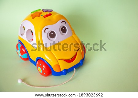 Children's toy car with face on green background. Copy space