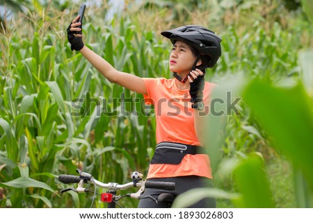 young asian woman cyclist with a phone searching for signal