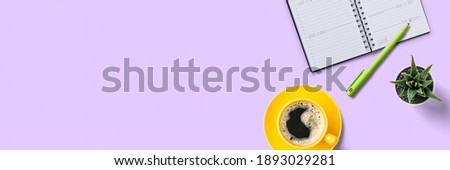 Top view of a workplace with office supplies on a lilac background