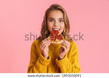 Excited beautiful blonde girl eating pizza at camera isolated over pink background