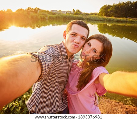 Couple taking photo of themselves with smart phone on romantic picnic date
