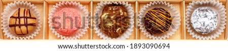 Set of chocolate truffle of dark and milk chocolate with orange glaze, strawberries (cranberries, raspberries), coconut and powdered sugar. Sweet gift of candy in a craft box. banner, long picture