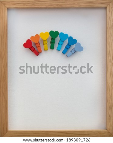 Valentine's Day congratulation concept. Wooden pins in the shape of hearts lined with a rainbow on a light background. positive atmosphere, birthday card, mother's day. minimalism. Copy space