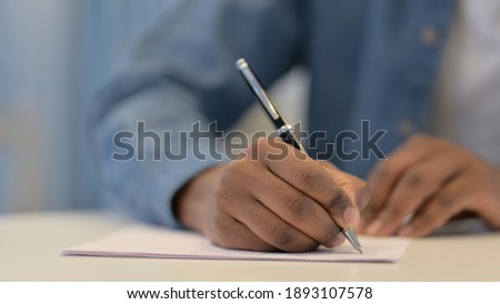 Hands of African Man Writing on Paper with Pen, Close Up