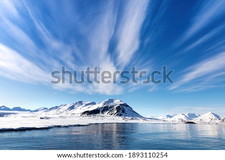 Blue sky, sea and snowy mountains in the beautiful fjords of Svalbard, a Norwegian archipelago between mainland Norway and the North Pole Royalty-Free Stock Photo #1893110254