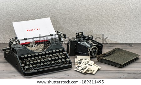 retro typewriter and vintage photo camera on wooden table. White paper page with sample text Memories