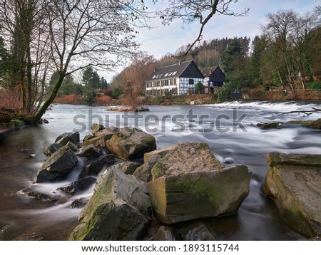 Half-timbered houses on the river bank. View on the Wipperkotten on the Wupper river, one of the landmarks of the Klingestadt Solingen in the Bergisches Land. Landscape photography Royalty-Free Stock Photo #1893115744