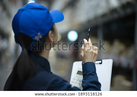 Female warehouse worker checking inventory in logistics warehouse
