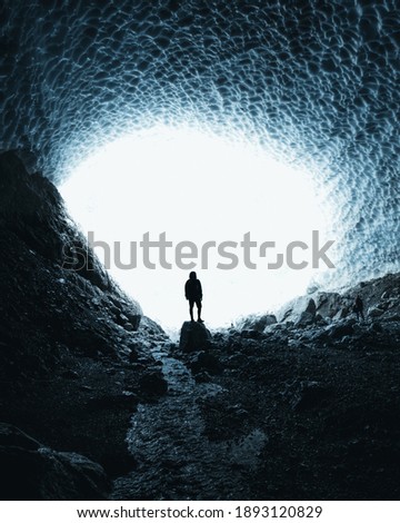 A lonely person standing on a rock in a cliff with the bright sunlight in the background