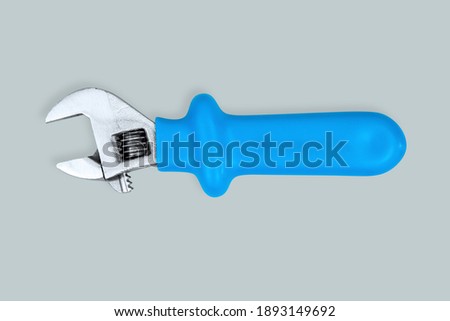Adjustable metal wrench with a rubberized handle on a gray background.