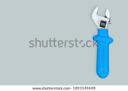 Adjustable metal wrench with a rubberized handle on a gray background.