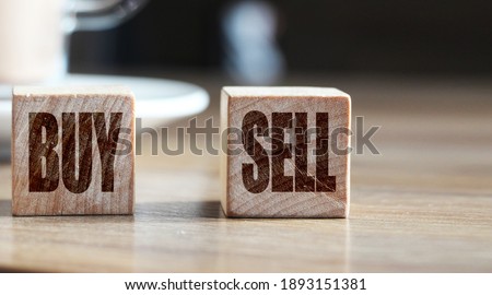 SELL or BUY - financial concept. Wooden cubes and cup with cacao on wooden table. Reselling business concept