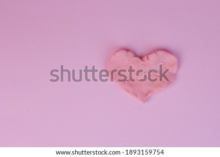A pink heart from modeling clay isolated on a pink background