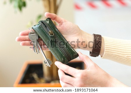 leather green key holder close up photo in human hands on shopping mall background