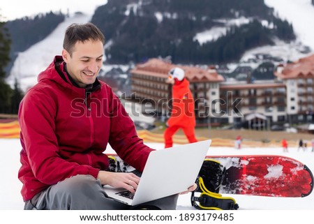 snowboarder typing on the laptop in the mountains winter