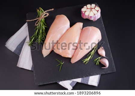 Chicken fillet with vegetables in a frying pan on a black background.Top view.