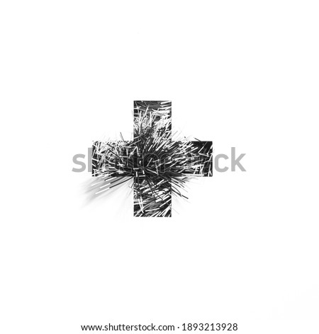 Plus summation sign or cross made of black tinsel and cut paper isolated on white. Monochrome typeface