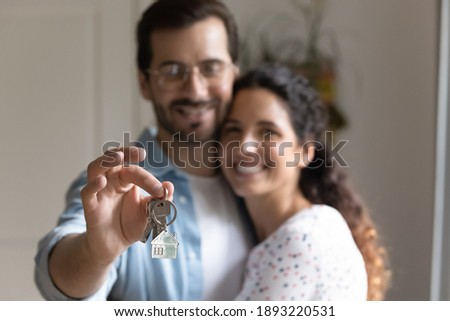 Close up happy husband hugging wife, satisfied customer holding keys from apartment, family purchase new house, real estate, first dwelling, celebrating moving day, relocation and mortgage concept Royalty-Free Stock Photo #1893220531