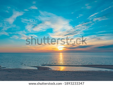 sea sunset with sun reflection in water under blue sky with white clouds