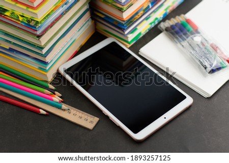There are many books, a tablet, pencils, pens and a notebook on the table. Distance learning concept, self-education.