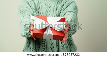 gives a gift held in the hands of his friend to the camera. portrait of a young woman of Afro appearance ethnic, black curly hair brunette. Clean, even skin of the face. good mood