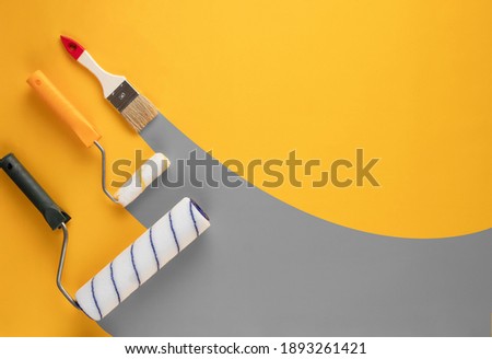 Gray stripes of paint from rollers and brushe on a yellow background. Home renovation concept. Royalty-Free Stock Photo #1893261421