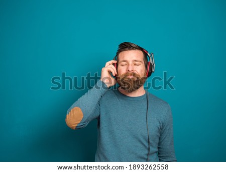 Young man over isolated green wall listening to music with headphones