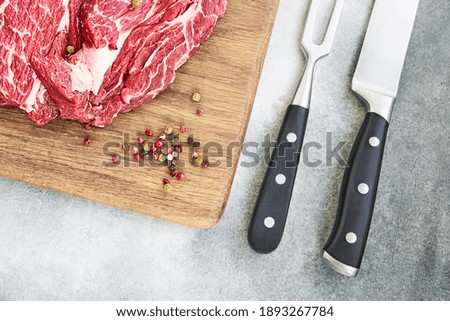 Fresh raw beef steaks with pepper on wooden cutting board board. Copy space, top view. Flat lay