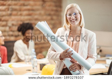 Young Woman Student architect holding blueprints. Smiling girl portrait. Architect woman with a plan. Architect are planning new project. Female construction engineer.