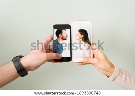 Close up of the hands of an attractive couple with smartphones and the photograph of a latin young woman and man in love and kissing. Love concept Royalty-Free Stock Photo #1893300748
