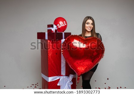 Valentines day holiday sale, young girl with heart shaped balloon with copy space and red gifts on gray background
