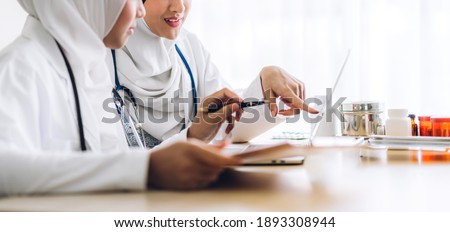 Professional medical two muslim asian woman doctor team with stethoscope in uniform working with laptop computer on desk in hospital.healthcare and medicine