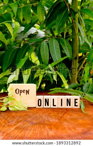 Open online in wooden blocks against natural wood and greenery background