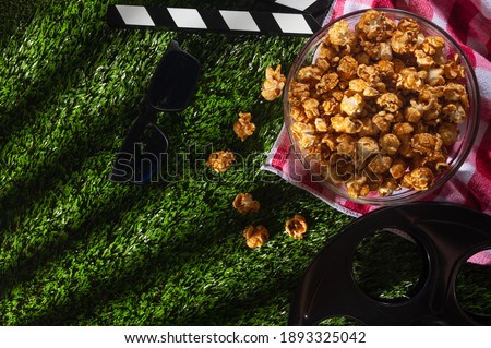 Movie clapperboard, popcorn boxes , 3d glasses on the grass background. Movie concept. Flat lay composition. Cinematic photo for blogs or design. View from above. Space for text.