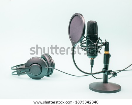 Condenser microphone and wired headphones on a blue background. Equipment for recording and reproducing sound.