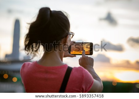 Woman take picture with smartphone in sunset Hong Kong