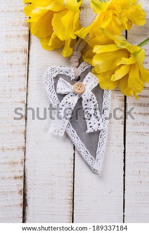 Fresh yellow flowers and heart on  wooden background. Top view, vertical.