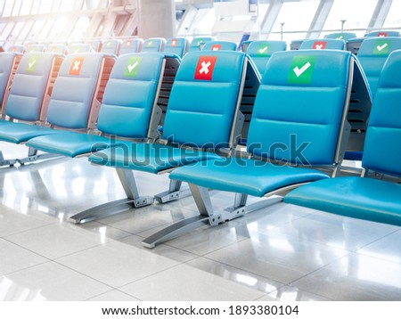 Empty waiting chairs with social distancing sign, green check mark and red cross mark. Blue chairs with social distancing symbol on seat in airport during the Covid-19 or Coronavirus pandemic.