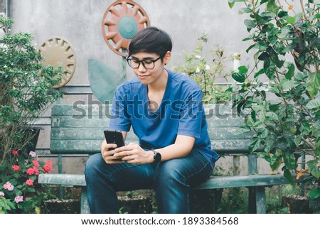 Social media with smartphone concept. Asian woman holding black mobile phone on hand using for take photo, internet marketing, e-learning, and shopping online in the garden. Selective focusing.