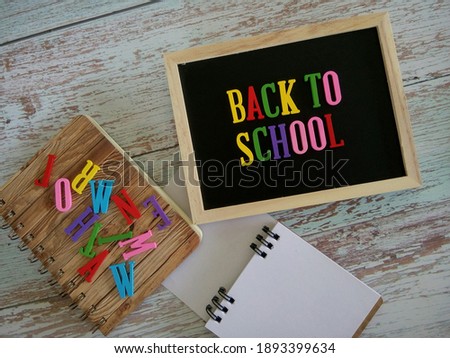 blackboard and note book with word BACK TO SCHOOL on wooden background