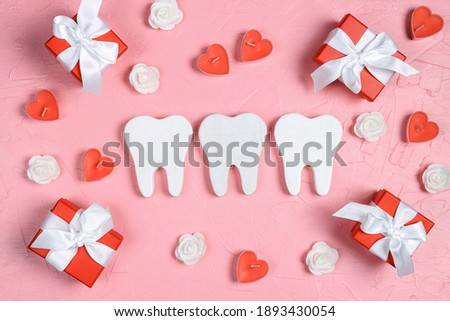 White teeth surrounded by gifts, hearts and roses on a pink background. Dental Valentine card. Valentine's day concept.  