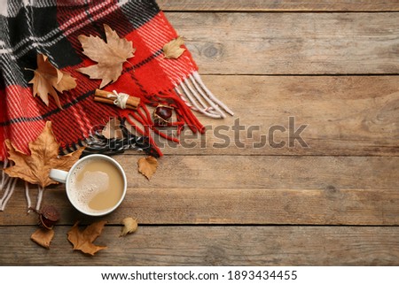 Flat lay composition with coffee and warm plaid on wooden table, space for text