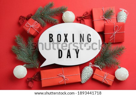 Speech bubble with phrase BOXING DAY and Christmas decorations on red background, flat lay