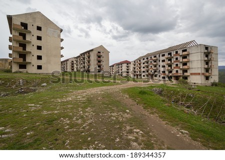 Abandoned block of flats under construction with road leading to them.  Brick and cement textures with grass all around