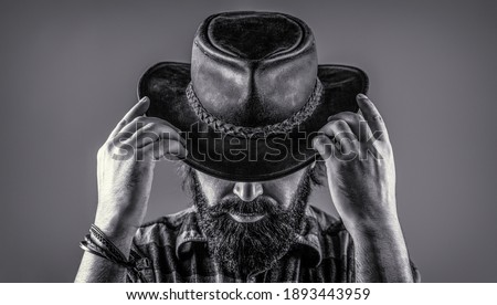Man unshaven cowboys. American cowboy. Leather Cowboy Hat. Portrait of young man wearing cowboy hat. Cowboys in hat. Handsome bearded macho. Black and white.