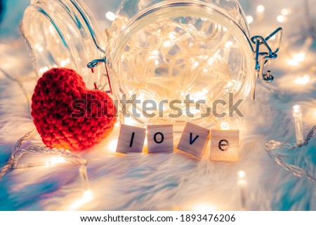 wooden letter block and heart shape on white cloth and light decorative bokeh. Love, Valentine and holiday concept.